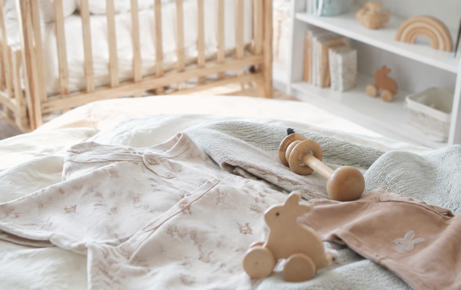 Babykleidung, Holzspielzeug und Strickdecke im Kinderzimmer – Beispiel für einen Shopify Baby Shop