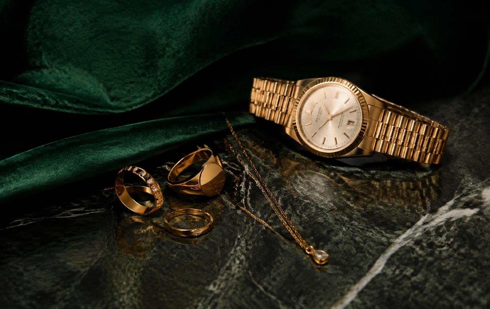 Goldringe, Halskette und Armbanduhr auf Marmor und Samt – Beispiel für einen Shopify Schmuck Shop